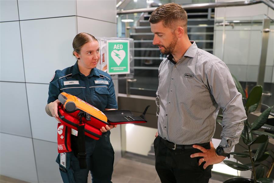 Two people in OMTID office looking at a defib