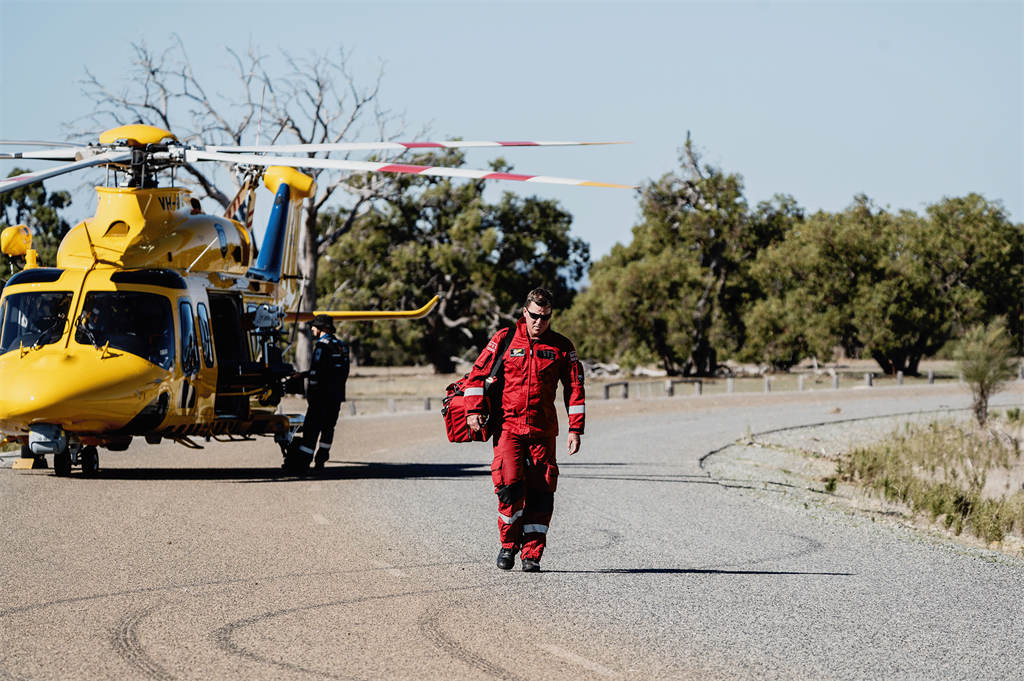 man in red uniform walking near landed yellow helicopter